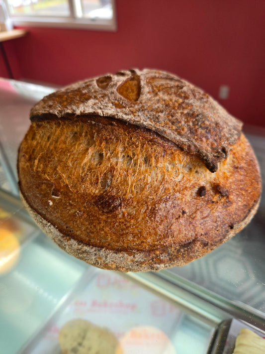 Roasted garlic & rosemary sourdough on a reflective surface with a blurred background