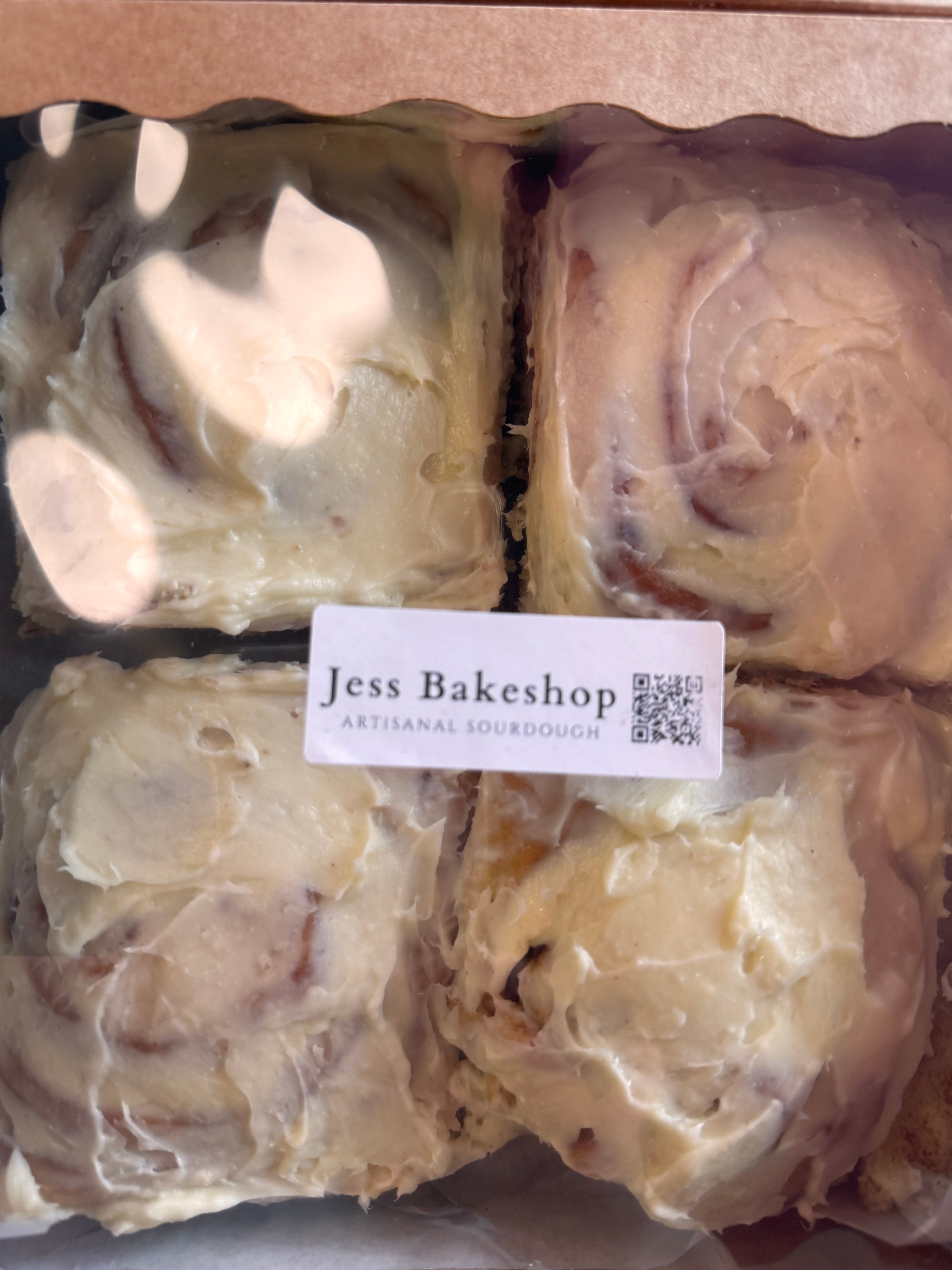 Cinnamon rolls in a box with a Jess Bakeshop label.