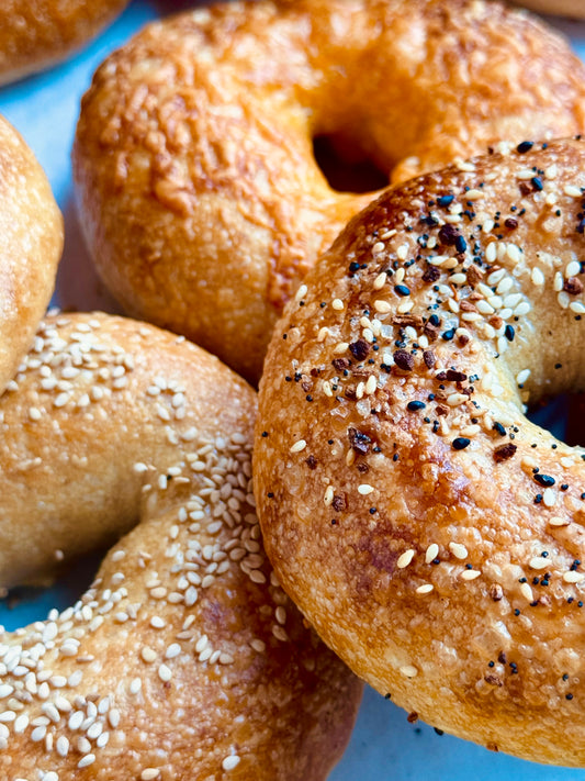 Close-up of bagels with sesame seeds and everything seasoning on a blue plate.