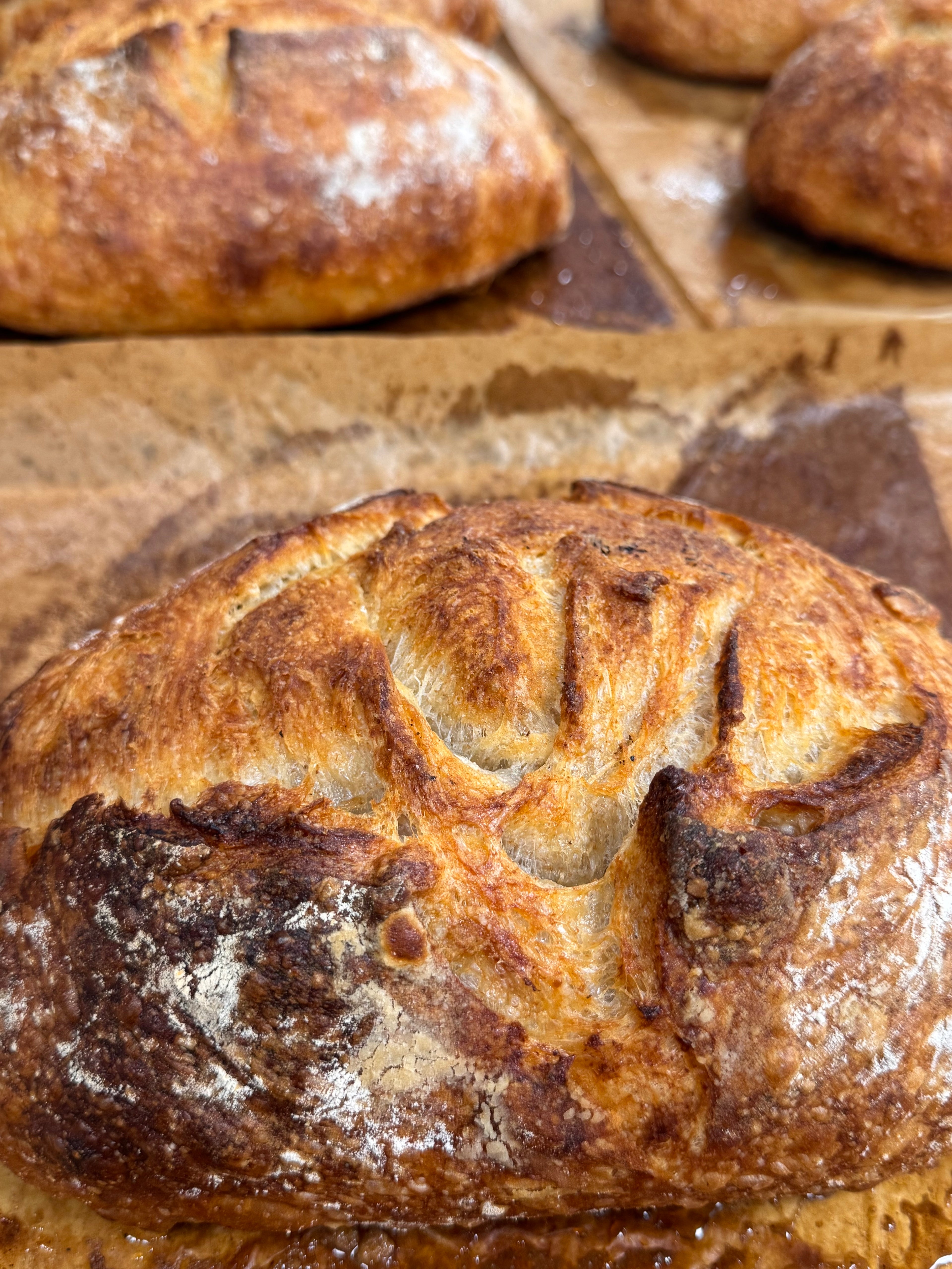 Close-up of a loaf of bread with a rustic crust on a stone surface.
