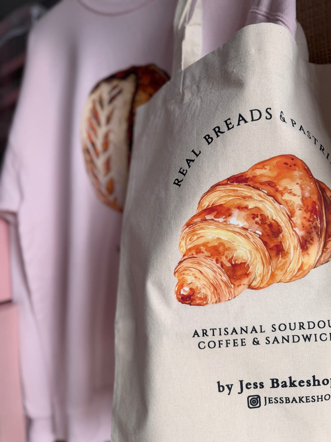 Tote bag with a croissant design and 'Real Breads & Pastries' text.